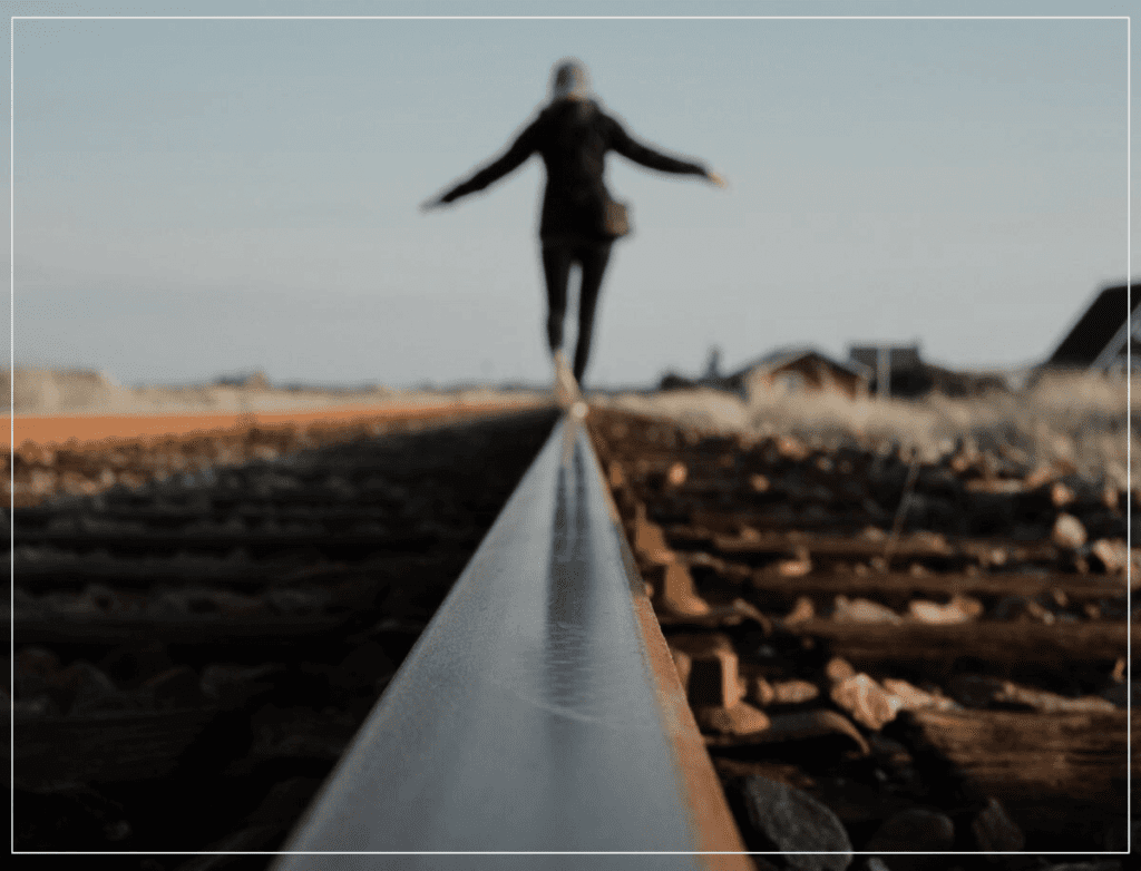 Produtividade pede equilíbrio entre recursos e resultados. Pessoa se equilibrando em um trilho de trem.
